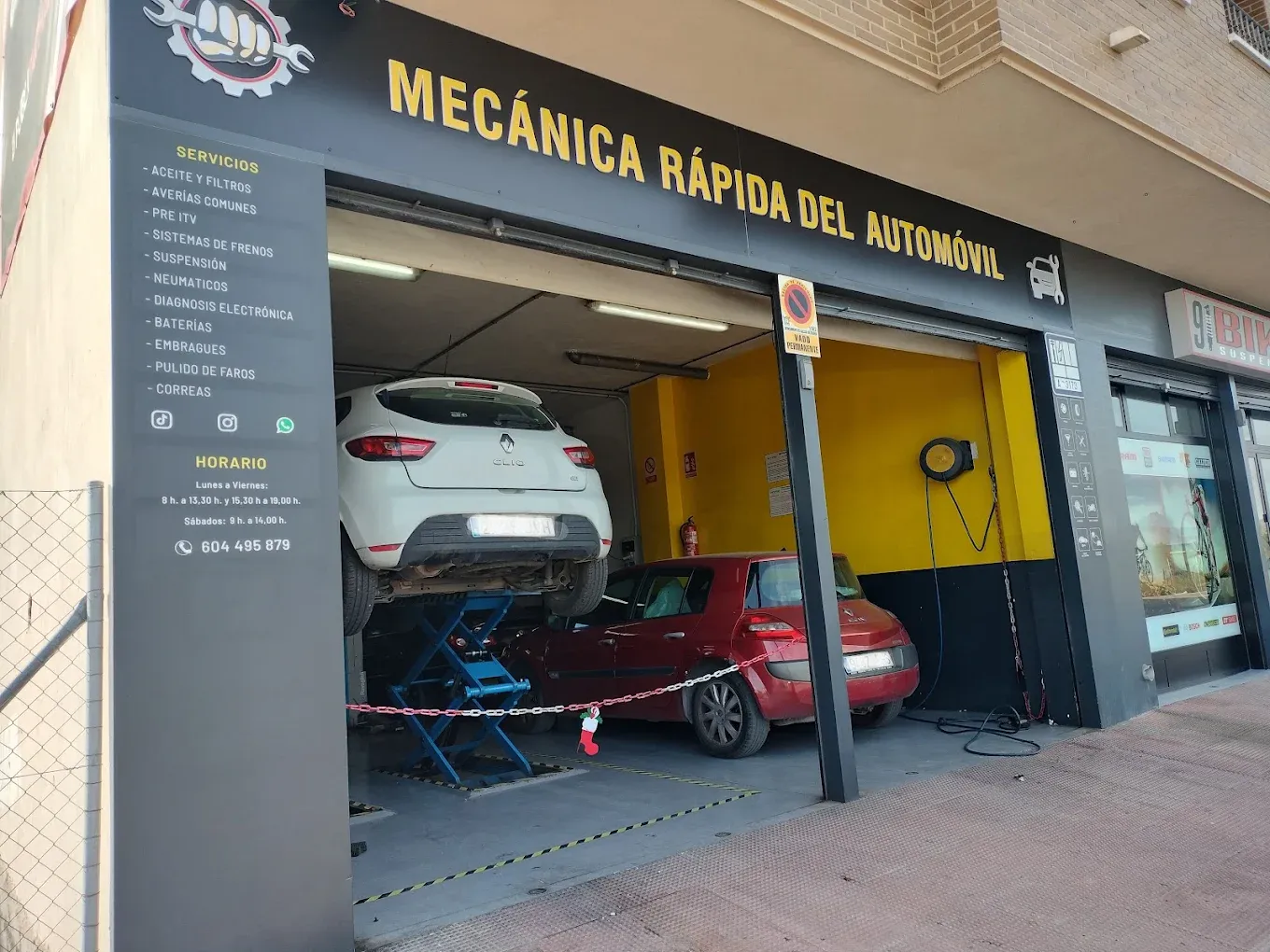 Fachada de Mecánica Rápida del Automóvil en Callosa de Segura: rótulo negro con letras amarillas y dos coches dentro del taller